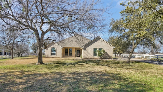 view of front of house with brick siding, a front yard, and fence