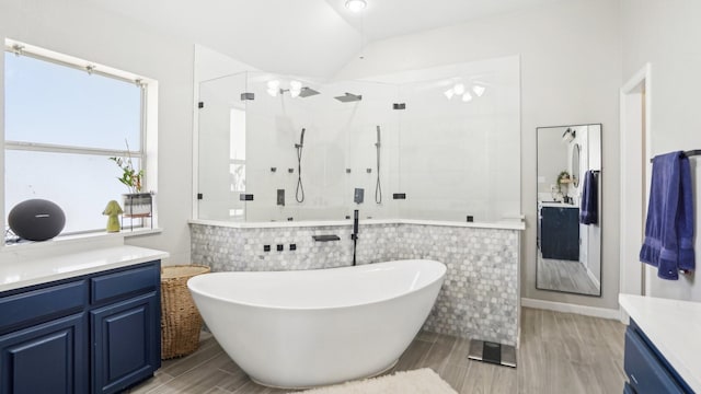 bathroom featuring a shower stall, wood tiled floor, lofted ceiling, a freestanding tub, and vanity