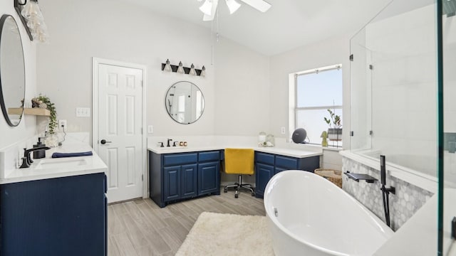 bathroom featuring ceiling fan, wood tiled floor, a freestanding bath, and a sink