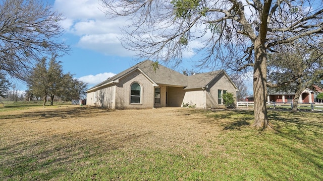 exterior space with brick siding, a lawn, and fence