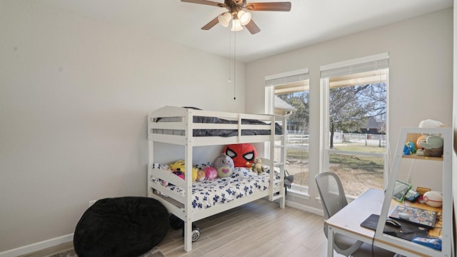 bedroom with ceiling fan, baseboards, and wood finished floors