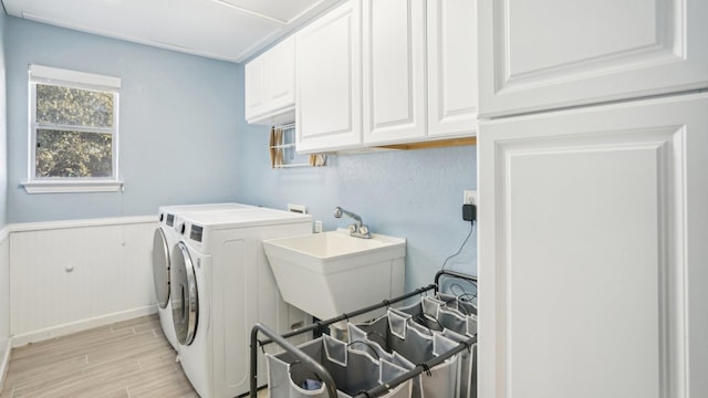 laundry room with wood finish floors, independent washer and dryer, a sink, cabinet space, and wainscoting