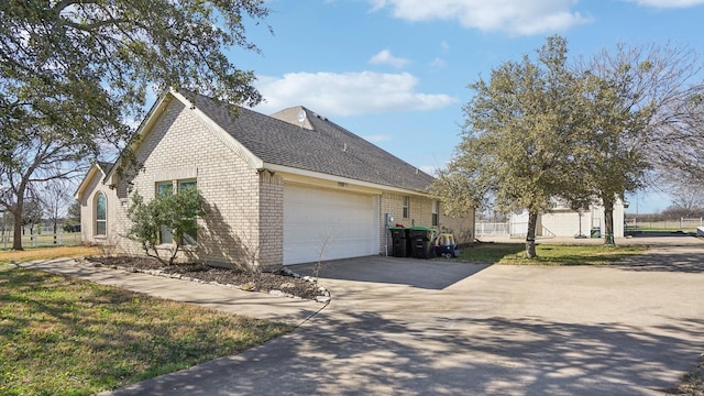 view of side of property with a garage, brick siding, and driveway