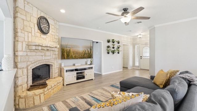 living room with visible vents, ornamental molding, a fireplace, light wood finished floors, and ceiling fan