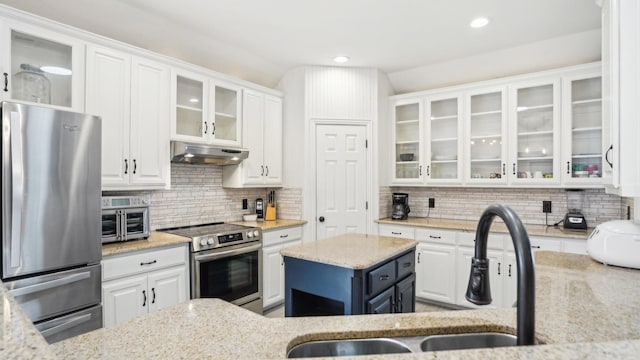 kitchen featuring under cabinet range hood, a sink, backsplash, white cabinetry, and appliances with stainless steel finishes