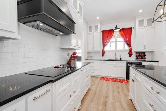 kitchen with white cabinets, light wood-style flooring, custom range hood, black appliances, and a sink