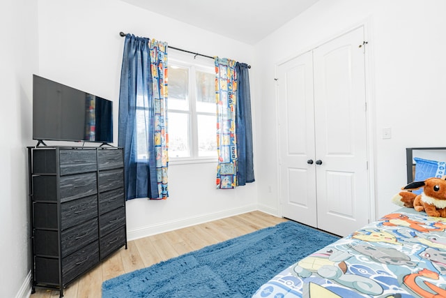 bedroom with a closet, wood finished floors, and baseboards