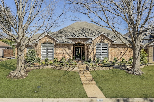 french country style house featuring brick siding, a front yard, and fence