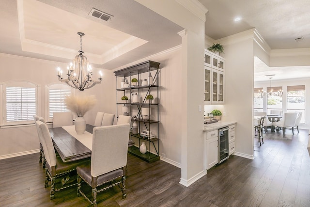 dining area featuring a tray ceiling, visible vents, an inviting chandelier, and beverage cooler