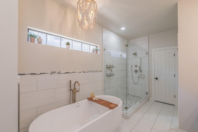 bathroom featuring a stall shower, tile walls, an inviting chandelier, tile patterned flooring, and a freestanding bath