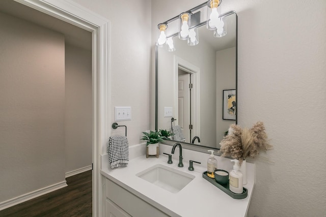 bathroom with baseboards, wood finished floors, and vanity