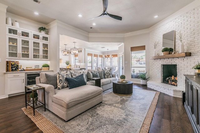 living room featuring wine cooler, dark wood-style floors, ceiling fan with notable chandelier, and ornamental molding