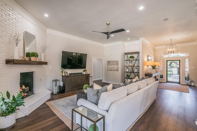 living area featuring visible vents, ornamental molding, a fireplace, ceiling fan, and dark wood-style flooring