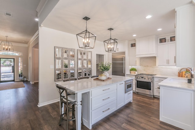 kitchen featuring visible vents, custom range hood, stainless steel built in fridge, a notable chandelier, and a sink