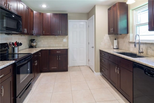 kitchen featuring light tile patterned floors, tasteful backsplash, a sink, light stone countertops, and black appliances