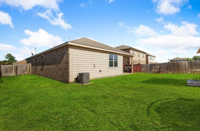 rear view of property featuring brick siding, a fenced backyard, and a yard