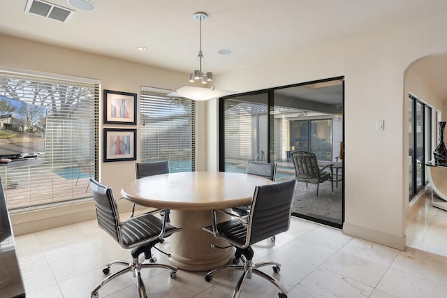 dining area featuring baseboards, visible vents, and arched walkways