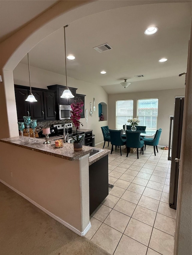 kitchen with visible vents, arched walkways, stainless steel appliances, dark cabinetry, and light tile patterned flooring