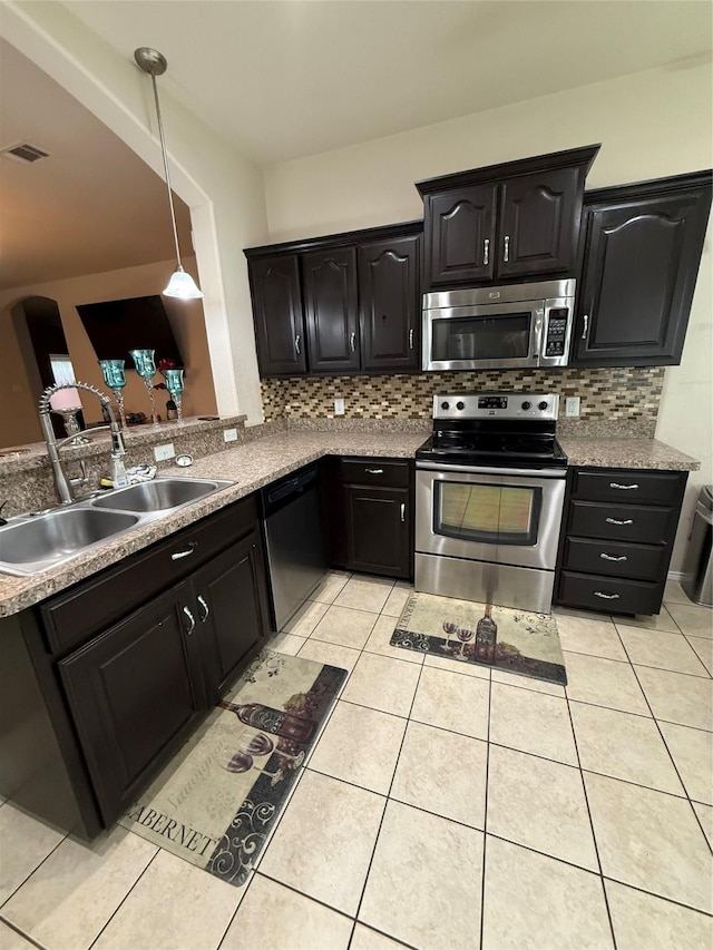 kitchen with light tile patterned floors, appliances with stainless steel finishes, backsplash, and a sink