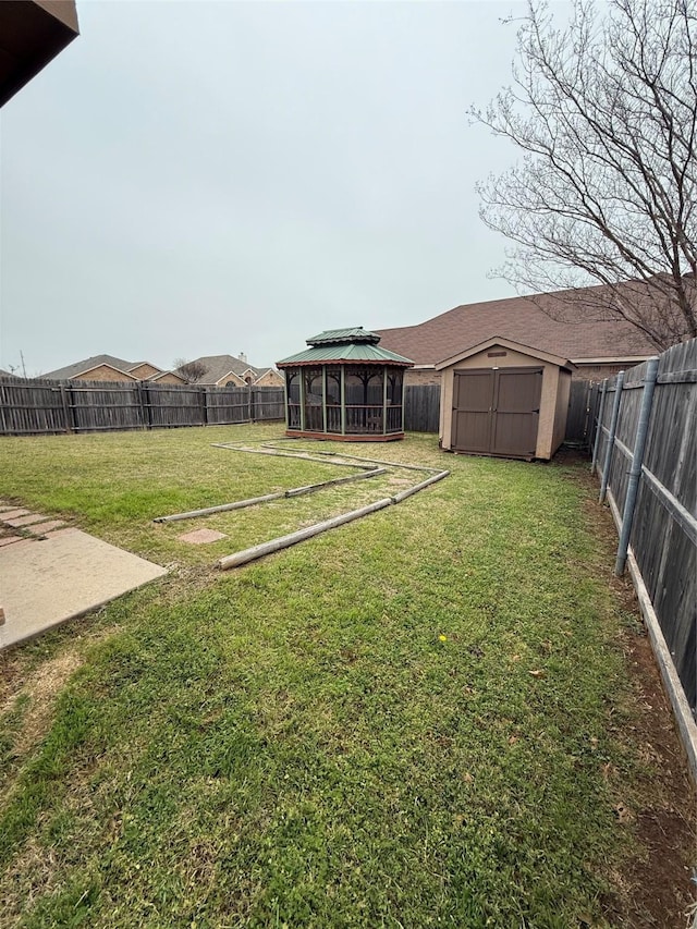 view of yard with a fenced backyard, a storage unit, an outbuilding, and a gazebo