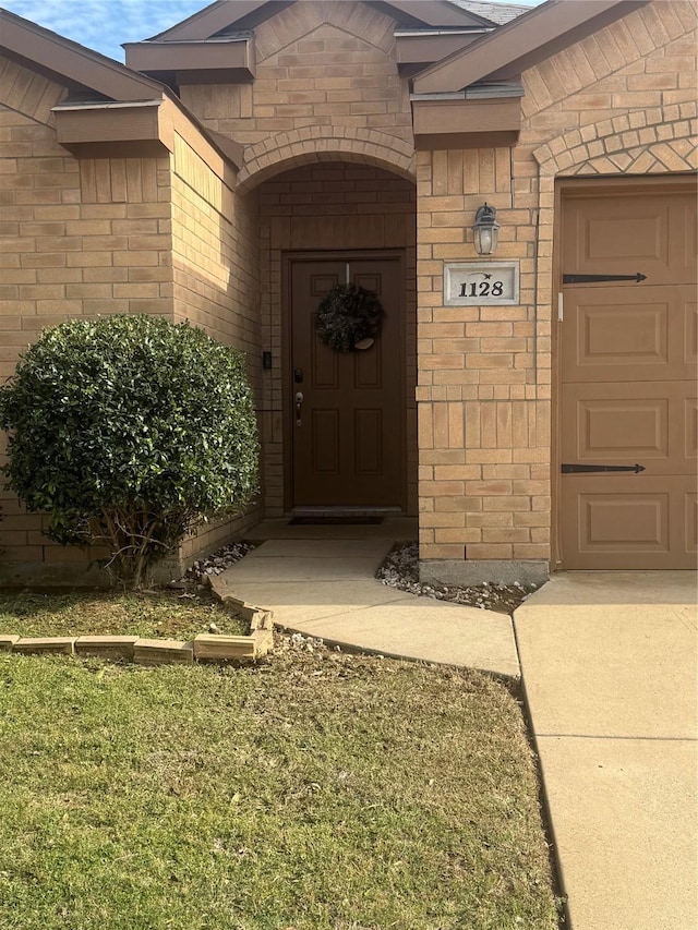 entrance to property with an attached garage and brick siding