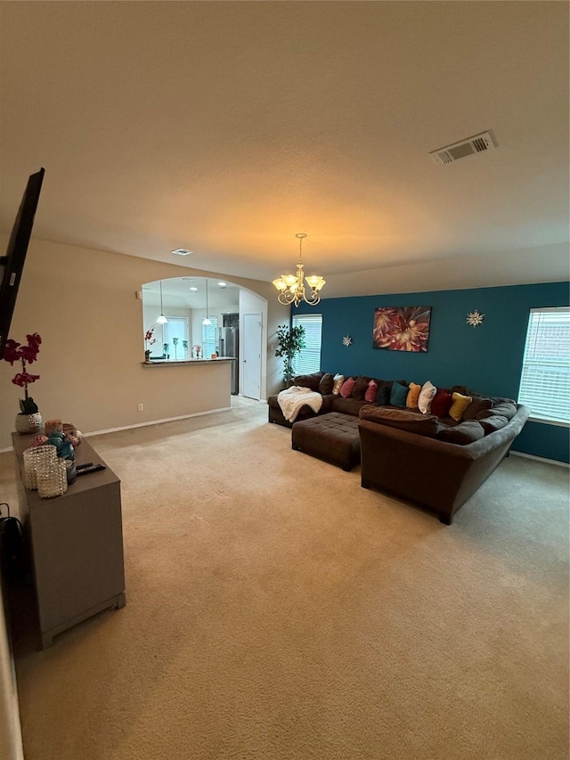 living area with arched walkways, a notable chandelier, light colored carpet, visible vents, and baseboards