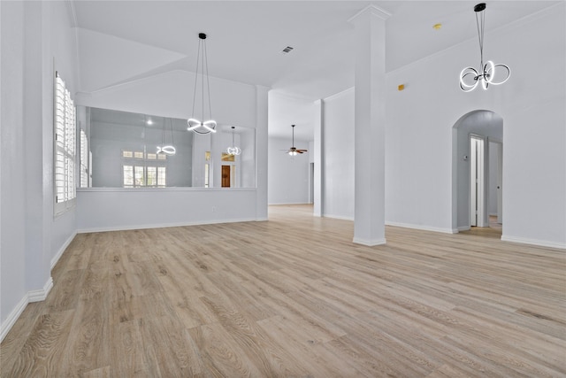 unfurnished living room featuring arched walkways, high vaulted ceiling, light wood-style flooring, ceiling fan with notable chandelier, and baseboards