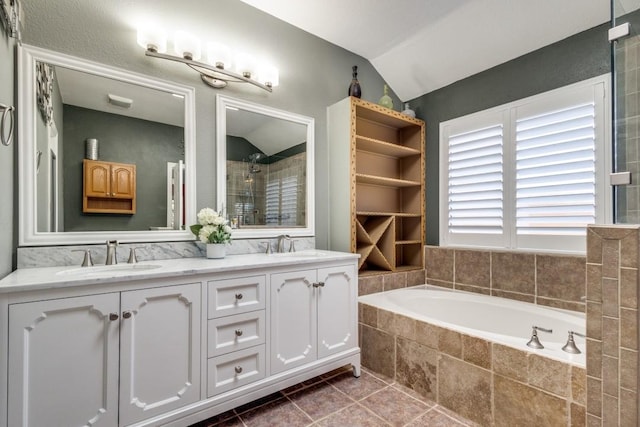 bathroom with lofted ceiling, tiled shower, a sink, and a garden tub