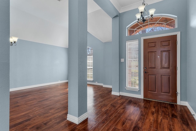 foyer entrance with dark wood finished floors, an inviting chandelier, ornamental molding, baseboards, and a high ceiling