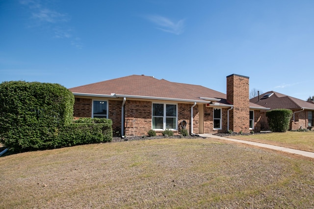 single story home featuring brick siding, a chimney, and a front lawn