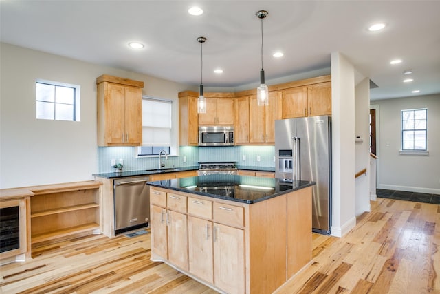 kitchen featuring a sink, light brown cabinetry, a kitchen island, and stainless steel appliances