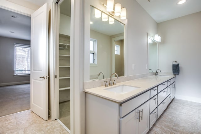 bathroom featuring double vanity, a sink, tile patterned flooring, and baseboards