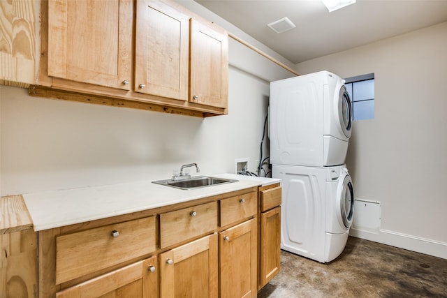 clothes washing area with stacked washer and dryer, visible vents, a sink, baseboards, and cabinet space