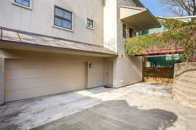 exterior space with stucco siding, a patio area, a garage, a standing seam roof, and metal roof