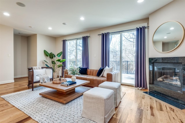 living area with a premium fireplace, wood finished floors, baseboards, and recessed lighting
