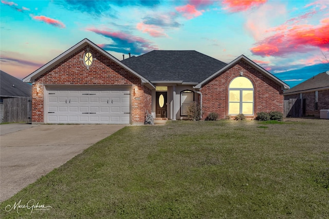 single story home with fence, a yard, an attached garage, concrete driveway, and brick siding