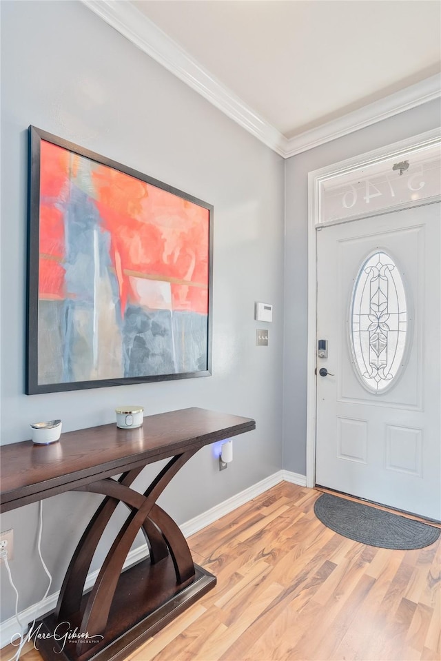 foyer entrance featuring wood finished floors, baseboards, and ornamental molding