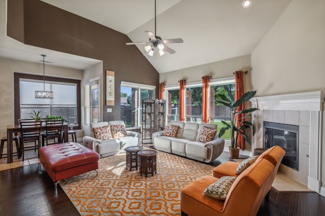 living room featuring ceiling fan, a tiled fireplace, high vaulted ceiling, and wood finished floors