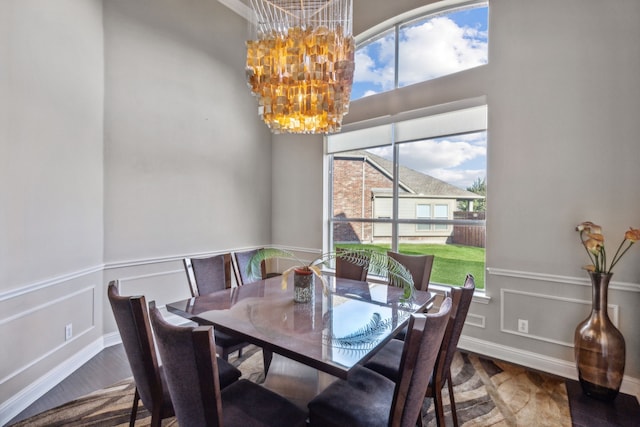 dining area featuring a chandelier, wainscoting, a decorative wall, and wood finished floors