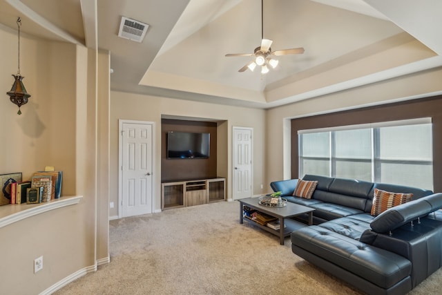 carpeted living area featuring ceiling fan, a tray ceiling, visible vents, and baseboards