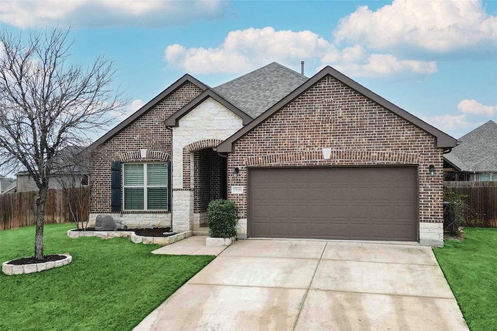 view of front facade with a shingled roof, brick siding, fence, and a front lawn