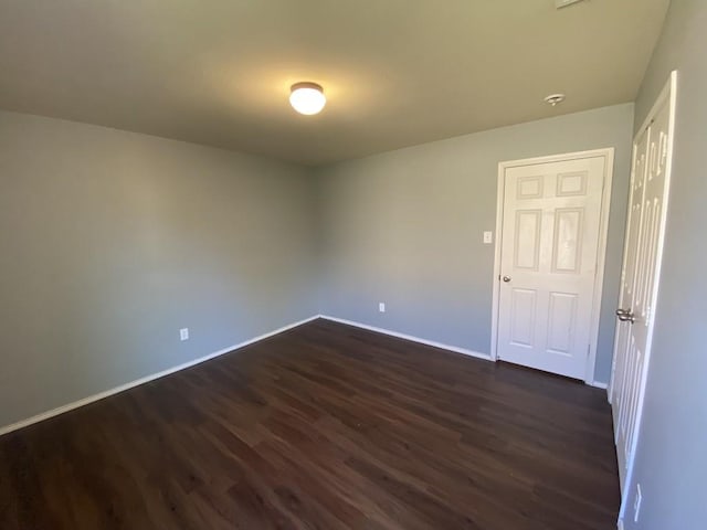 unfurnished room with dark wood-style floors and baseboards