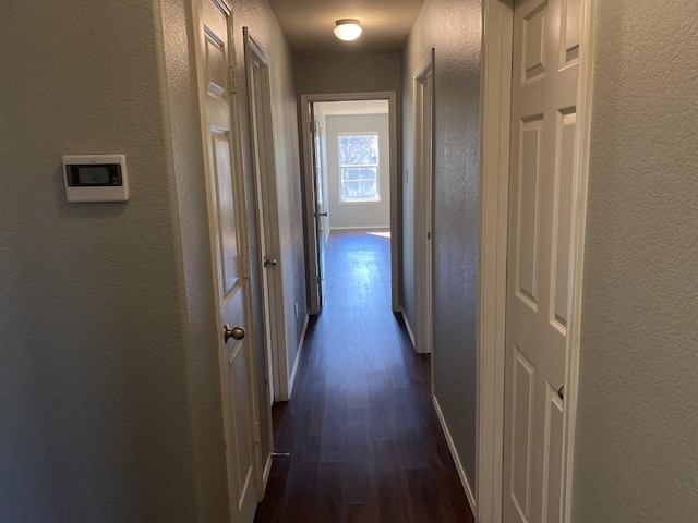 hall with baseboards, dark wood-style flooring, and a textured wall