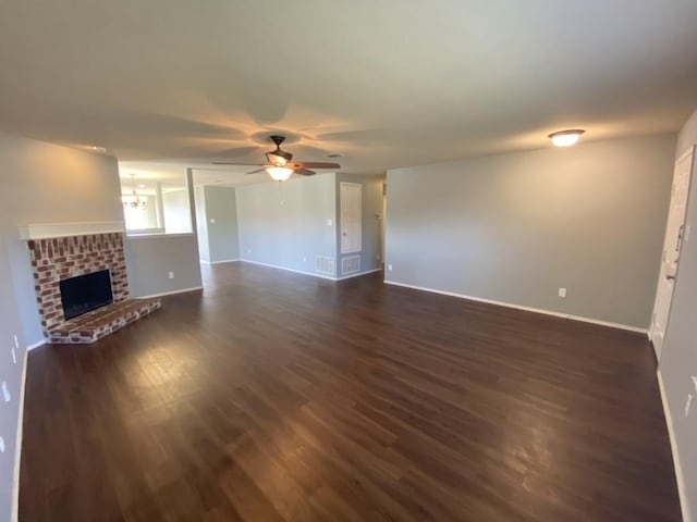 unfurnished living room featuring dark wood-style floors, ceiling fan, a fireplace, and baseboards