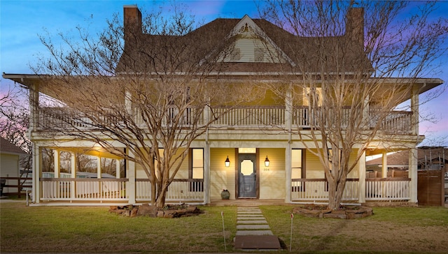 country-style home featuring covered porch, a yard, and a balcony