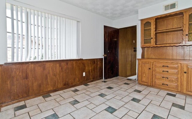 interior space with wainscoting, visible vents, and wooden walls