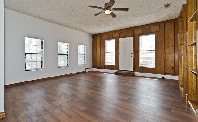 empty room with visible vents, dark wood-type flooring, ceiling fan, a textured ceiling, and baseboards