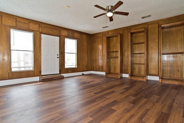 interior space with dark wood-type flooring, a wealth of natural light, visible vents, and a textured ceiling