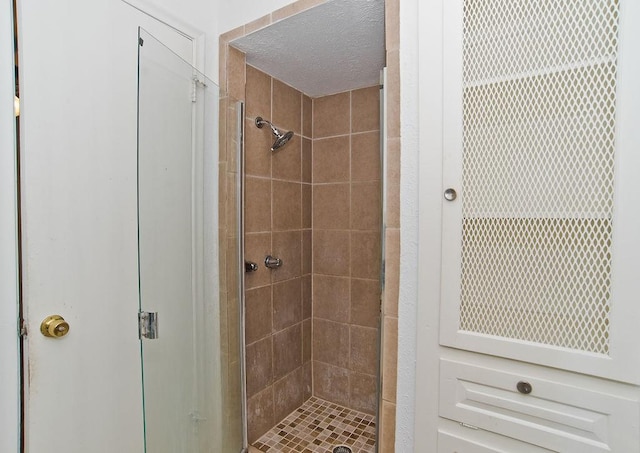 bathroom with a shower stall and a textured ceiling