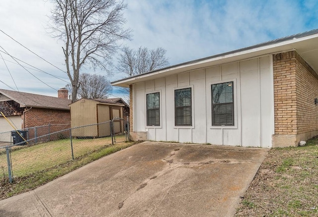 view of home's exterior featuring an outbuilding, brick siding, fence, a yard, and board and batten siding